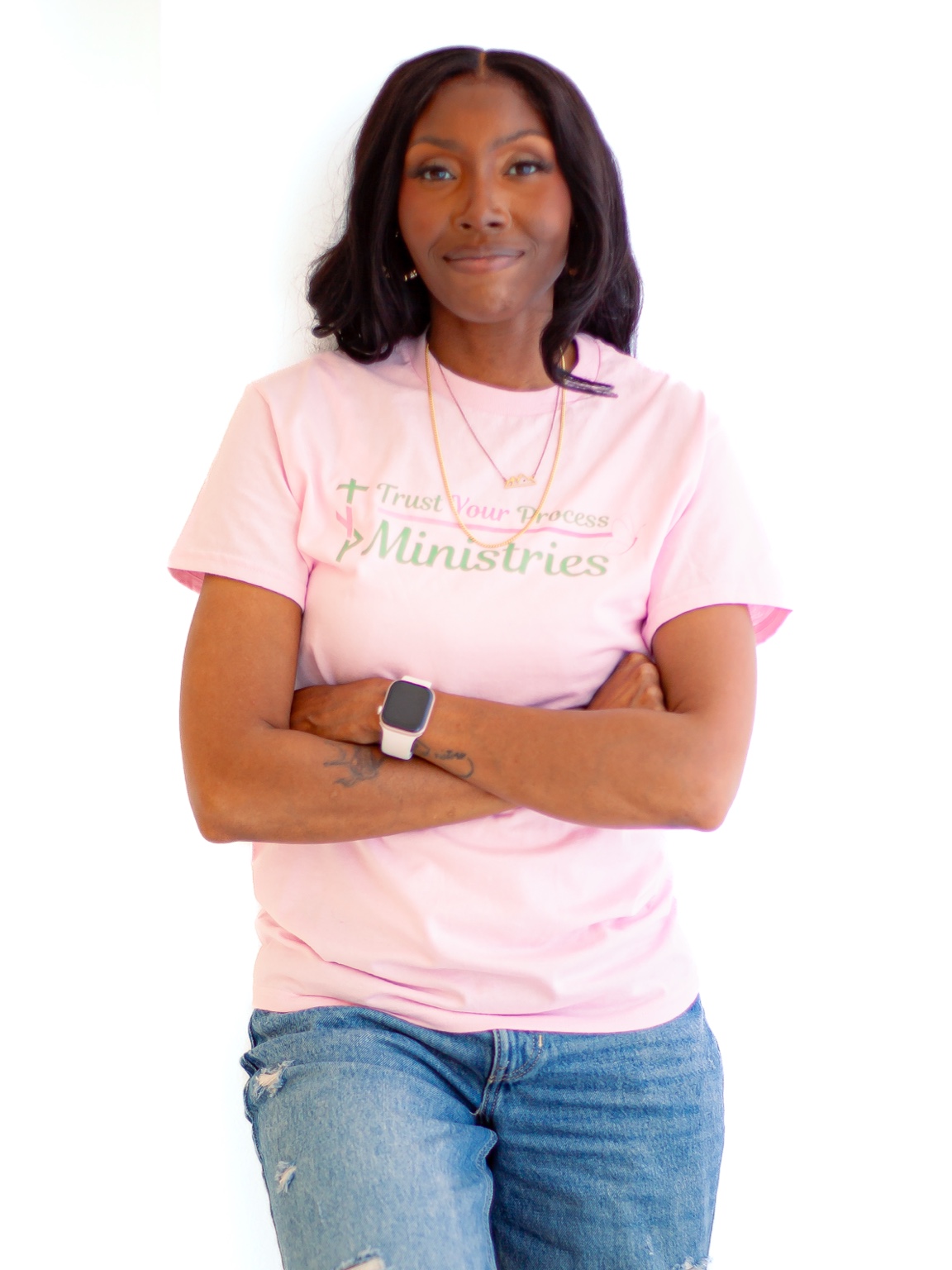 Shaquanna Jones in a pink Trust Your Process Ministries shirt with her arms folded